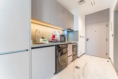 a kitchen with white cabinets and a washer and dryer at Studio with Glimpse of Burj Khalifa, Minutes from Downtown Dubai, MAG 930, Mohammad Bin Rashid City by Deluxe Holiday Homes in Dubai