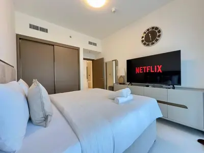 a bedroom with a bed with a tv on the wall at Elegant and Stylish 1BR, Grand Blue in Dubai