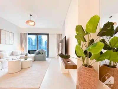 a living room with white furniture and a large plant at Luxurious Burj Crown 2BR Apartment with Balcony in Dubai