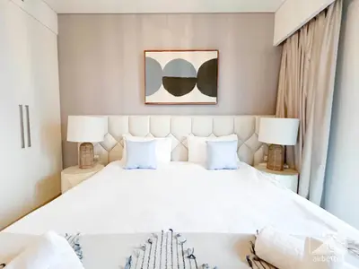 a bedroom with a large white bed with two lamps at Luxurious Burj Crown 2BR Apartment with Balcony in Dubai