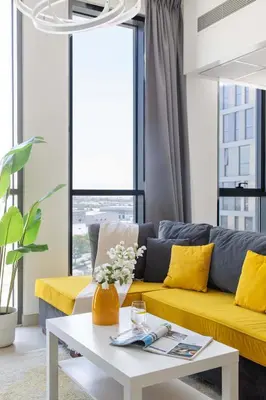 a living room with a yellow couch and a table at Frank Porter - Midtown By Deyaar - Dania 2 in Dubai
