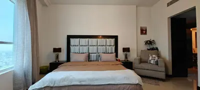 a bedroom with a large bed and a chair at JLT 1BR Marina Skyline View in Dubai