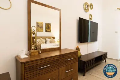a bedroom with a dresser with a mirror and a tv at Modern Studio Fully Furnished Oxford Residence in Dubai