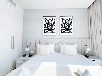 a white bedroom with a white bed with three pictures on the wall at Full Luxury at Burj Crown 2B with City Views in Dubai