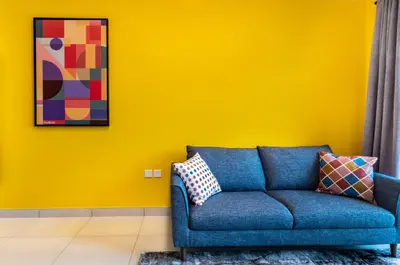 a blue couch in a room with a yellow wall at YouCo Dubai apart-hotel in Dubai