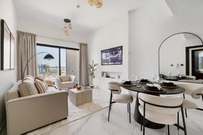 a white living room with a table and a couch at New 1BR with Full Balcony Gym Pool and Sauna in Dubai
