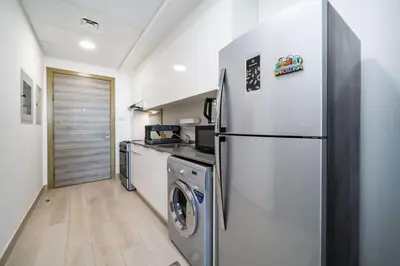 a kitchen with a refrigerator and a washer and dryer at Luxury JVC Studio in a Great Location in Dubai