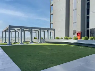 a rendering of a building with a lawn in front at Luxury JVC Studio in a Great Location in Dubai