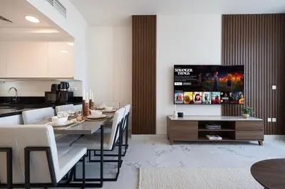 a living room with a dining table and a kitchen at 5 Star Amenities 10 Mins Downtown Kite Beach in Dubai