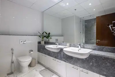 a bathroom with two sinks and a toilet and a mirror at 5 Star Amenities 10 Mins Downtown Kite Beach in Dubai