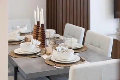 a dining table with white dishes and candles on it at 5 Star Amenities 10 Mins Downtown Kite Beach in Dubai