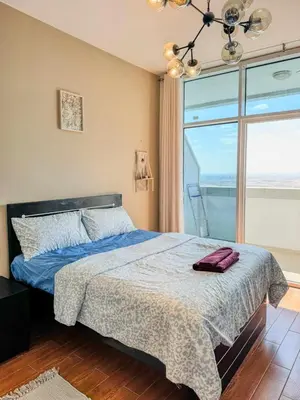 a bedroom with a bed and a large window at Luxury Studio in JVT in Dubai