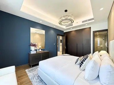 a bedroom with a large white bed and a blue wall at Trophy-Luxe Living in a Blue-Hued Haven in Dubai