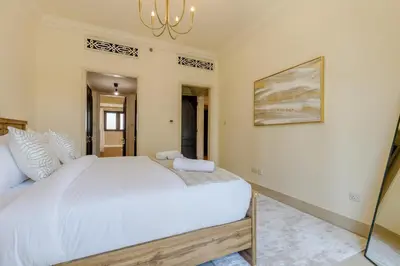 a bedroom with a large white bed and a chandelier at Al Tajer Residence, Oldtown - 1BR Apartment - Allsopp & Allsopp in Dubai