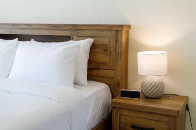 a bed with a wooden headboard and a table with a lamp at Al Tajer Residence, Oldtown - 1BR Apartment - Allsopp & Allsopp in Dubai