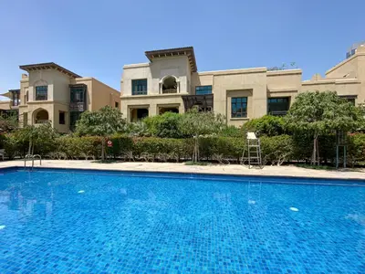 a large house with a swimming pool in front of it at Al Tajer Residence, Oldtown - 1BR Apartment - Allsopp & Allsopp in Dubai