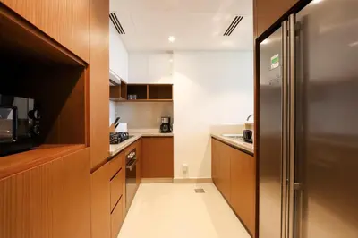 a small kitchen with wooden cabinets and a stainless steel refrigerator at Livbnb Creekfront 2BR with Skyline Views Steps to Creek Marina in Dubai