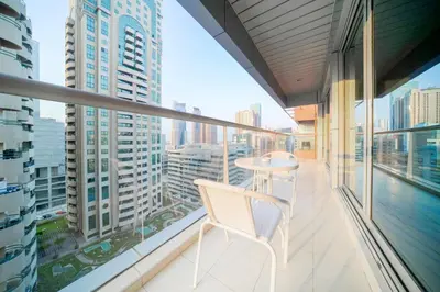 a balcony with a white chair and a view of a city at Stella Stays Barsha Heights in Dubai
