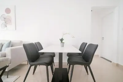 a dining room with a white table and four chairs at Stella Stays Barsha Heights in Dubai