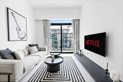a living room with a couch and a tv at Vayk - Modern 2BR with Private Plunge Pool in JVC in Dubai