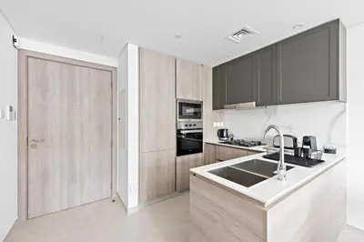 a kitchen with wooden cabinets and a sink at Vayk - Modern 2BR with Private Plunge Pool in JVC in Dubai