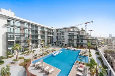 an apartment complex with a swimming pool and palm trees at Vayk - Modern 2BR with Private Plunge Pool in JVC in Dubai