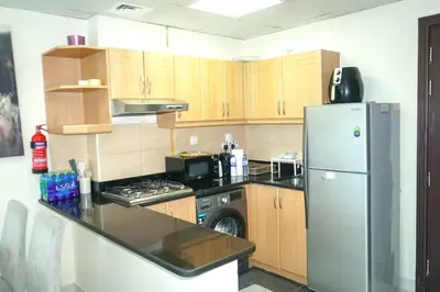 a kitchen with wooden cabinets and a refrigerator at Stylish 1BR in Elite 7 Sports City in Dubai