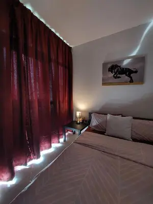 a bedroom with red curtains and a bed and a table at Damac Hills 2- 3BR Townhouse - Homeyvillas in Dubai