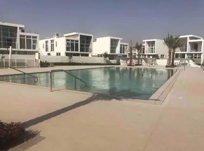 a large swimming pool in front of some apartments at Damac Hills 2- 3BR Townhouse - Homeyvillas in Dubai