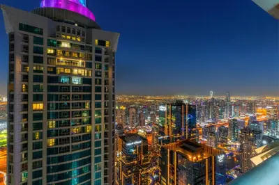 a city skyline at night with a tall building at Luxury 2BR with City Skyline Views Steps to JBR Beach & Marina Mall in Dubai