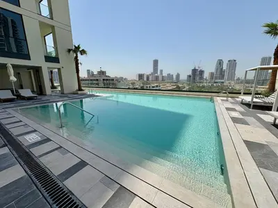 a large swimming pool with a view of the city at Stylish Studio in JVC with Pool, Gym, Balcony & Modern Comforts in Dubai