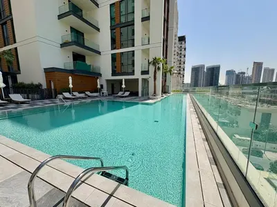 a large swimming pool with chairs and a building at FIRST CLASS Studio Unwind in Style in Dubai