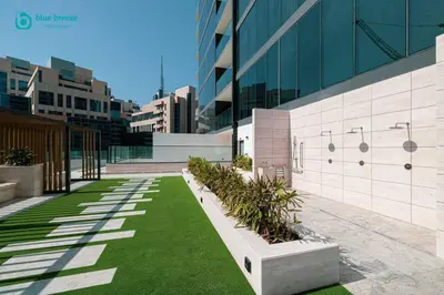 a courtyard with green grass in front of a building at Blue Breeze - Luxurious 1BR with Private Jacuzzi & Burj View in Dubai