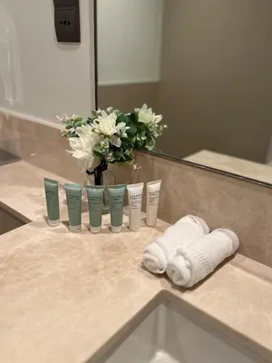 a bathroom counter with a vase of flowers and towels at Act tower-1BR near Burj Khalifa in Dubai