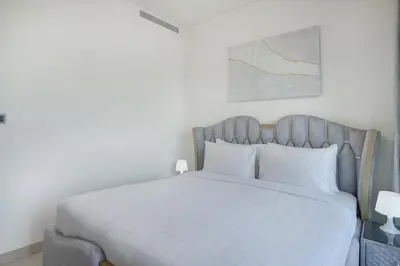 a bedroom with a white bed with a gray headboard at EasyGo-Modern, Distinguished with Sofa Bed in Dubai