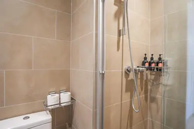 a bathroom with a shower with bottles of wine at EasyGo-Modern, Distinguished with Sofa Bed in Dubai