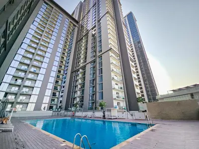 a large apartment complex with a swimming pool in front of two tall buildings at EasyGo-Modern, Distinguished with Sofa Bed in Dubai
