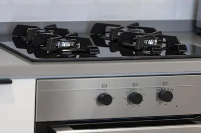 a stove top with black burners on top of it at Restay Homes - Fancy 2BR in Belgravia Heights - Pool access in Dubai