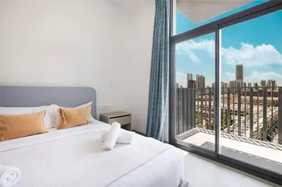 a bedroom with a white bed and a large window at Restay Homes - Fancy 2BR in Belgravia Heights - Pool access in Dubai