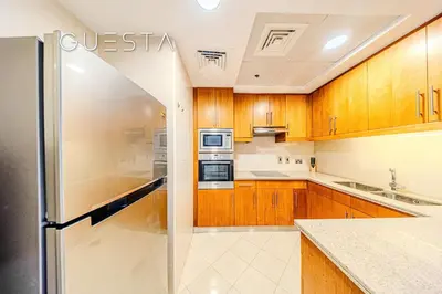 a kitchen with wooden cabinets and a stainless steel refrigerator at Trident Grand Residence 1 BDR plus Guest Bedroom, Dubai Marina in Dubai