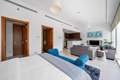 a bedroom with a large bed and blue chairs at Elegant Studio with Burj Khalifa Skyline Views in Dubai
