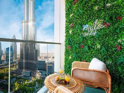 a table and chairs on a balcony with a green wall at Grande Signature Residences by Prestige Nest in Dubai