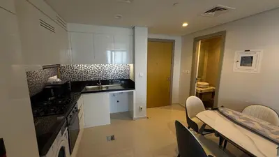 a kitchen with white cabinets and a table and chairs at Aykon city in Dubai
