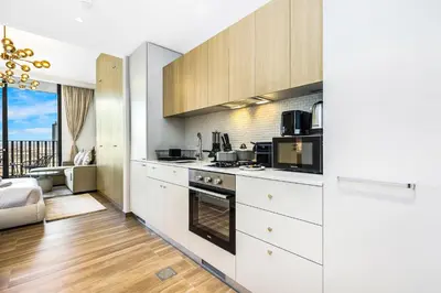 a kitchen with white appliances and a living room at FIRST CLASS Studio Stylish Comfort in Dubai