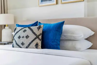 a bed with blue and white pillows on it at GuestReady - Jumeirah Village haven with pool view in Dubai