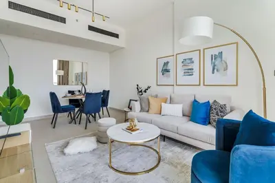 a living room with a white couch and blue chairs at GuestReady - Jumeirah Village haven with pool view in Dubai