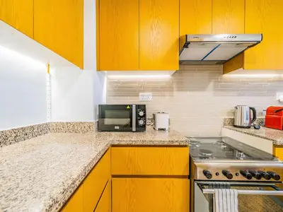 a kitchen with yellow cabinets and a microwave at Chic Getaway with Balcony & Burj Khalifa View in Dubai