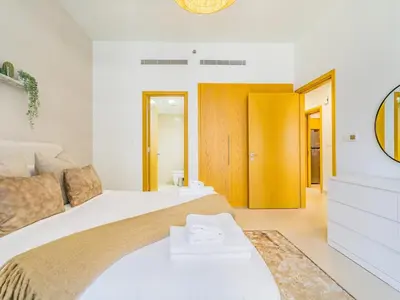 a white bedroom with a large bed and a yellow door at Chic Getaway with Balcony & Burj Khalifa View in Dubai