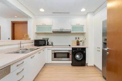 a kitchen with white cabinets and a washer and dryer at Marina Residence 6 - Luxurious Two Bedroom and Maid's - Lake and Sea View in Dubai