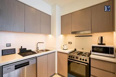 a kitchen with wooden cabinets and a sink and a microwave at Stylish Downtown Dubai Stay Act 1 Act 2 Tower 1 in Dubai